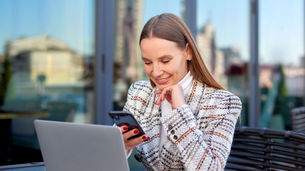 Woman Smiling at Phone Behind Laptop
