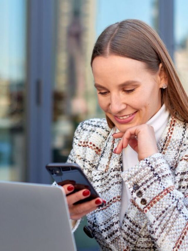 Woman Smiling at Phone Behind Laptop