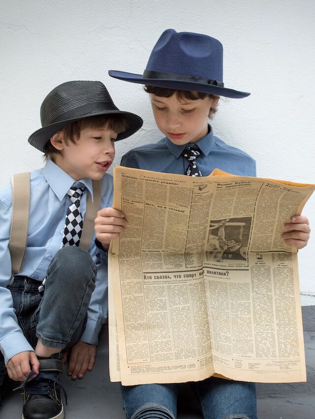 Two Kids Reading A Newspaper Stock