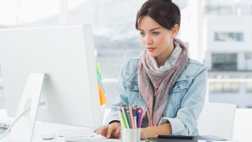 Woman Wearing A Scarf Typing On A Desktop Computer