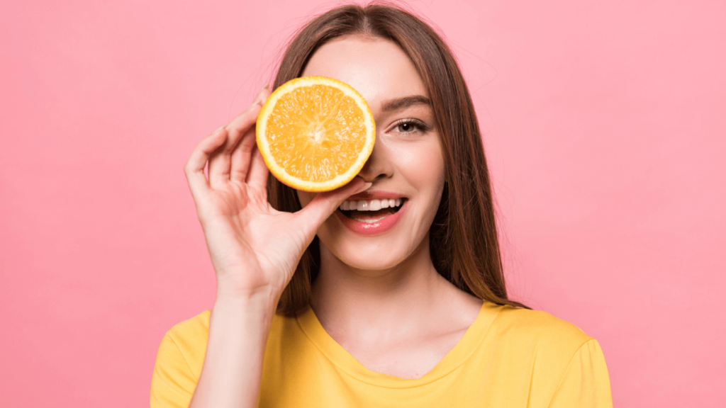 Woman Holding Orange (Food) in Front of Her Face Smiling MSN