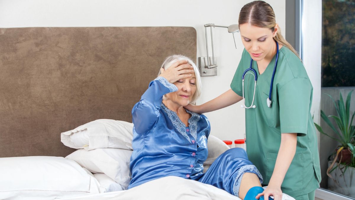 Caretaker Nurse Using Hot Water Bag On Senior Woman MSN