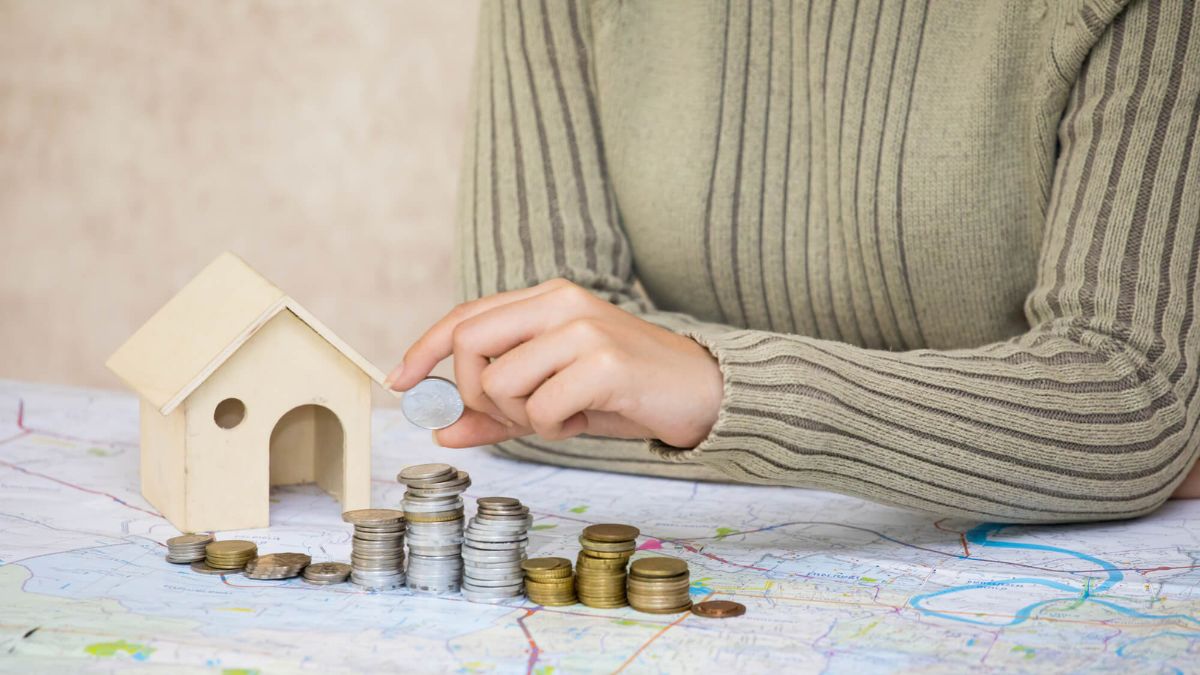 Girl Placing Coin On Stack Beside Wooden House MSN