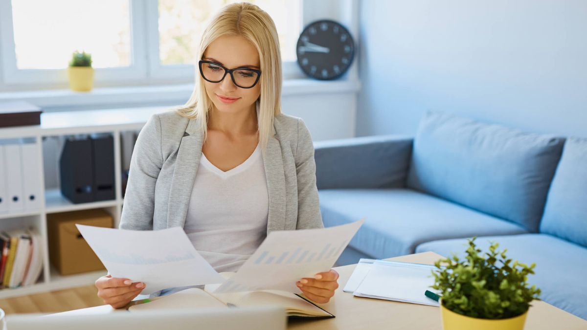 Woman Running A Small Business Seated On Desk With Papers MSN