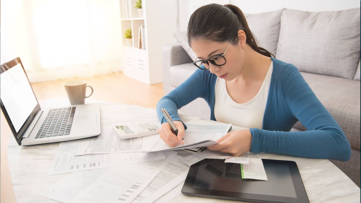 Woman Using Laptop And Tablet To Calculate Bills MSN