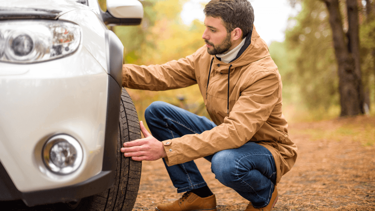 Man Checking Tire Pressure on Car in Woods MSN