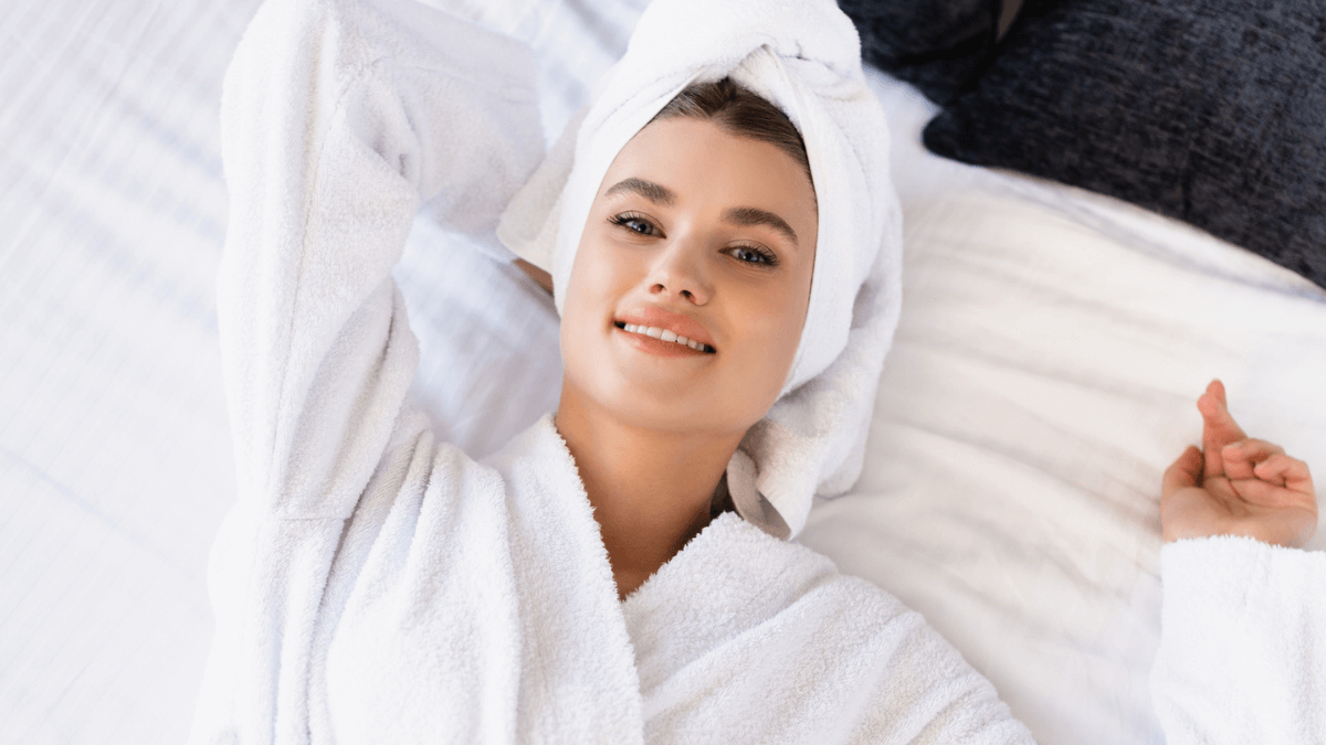 Woman Lying on Bed in Bathrobe with Towel on head Smiling Happy MSN