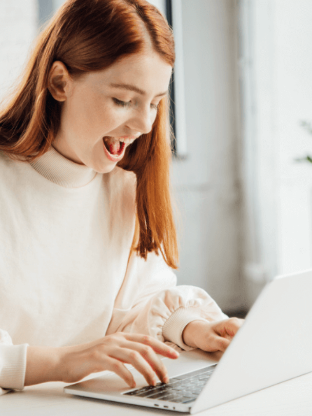 Smiling girl sitting at table and using laptop at home