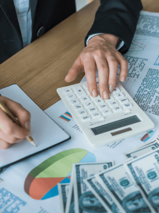 Cropped image of financier using calculator and writing something to notebook in office