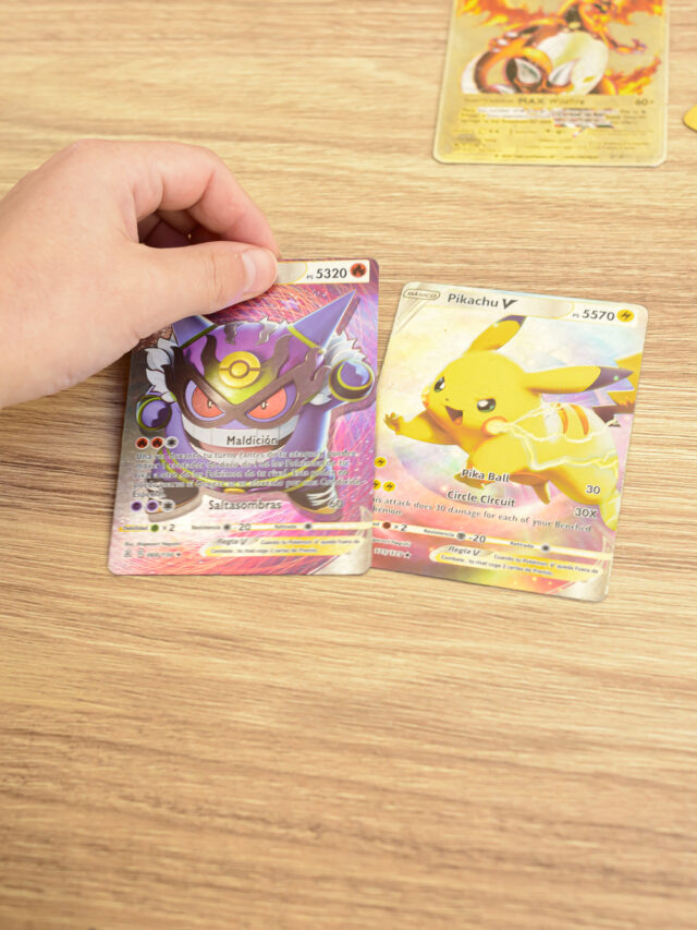 A child's hands placing rare collectible Pokemon trading cards on a wooden table.