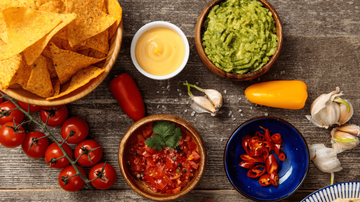 food- Mexican nachos with guacamole, cheese sauce and salsa on table msn