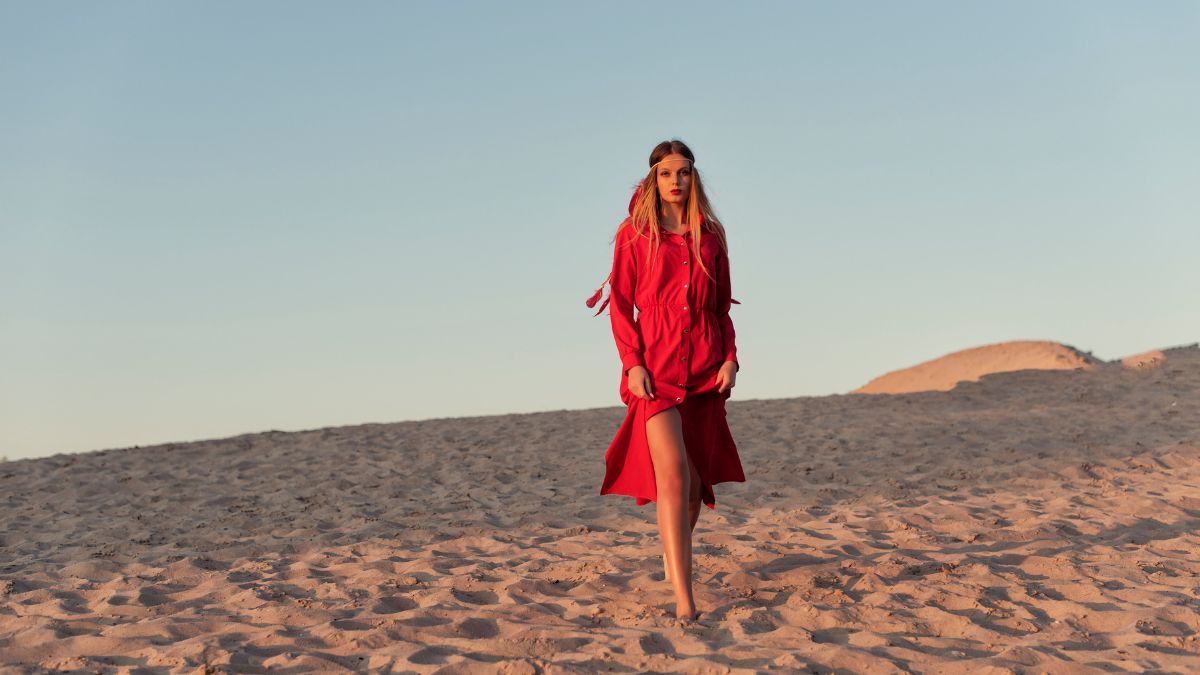 Beautiful woman in red walking on the sand MSN