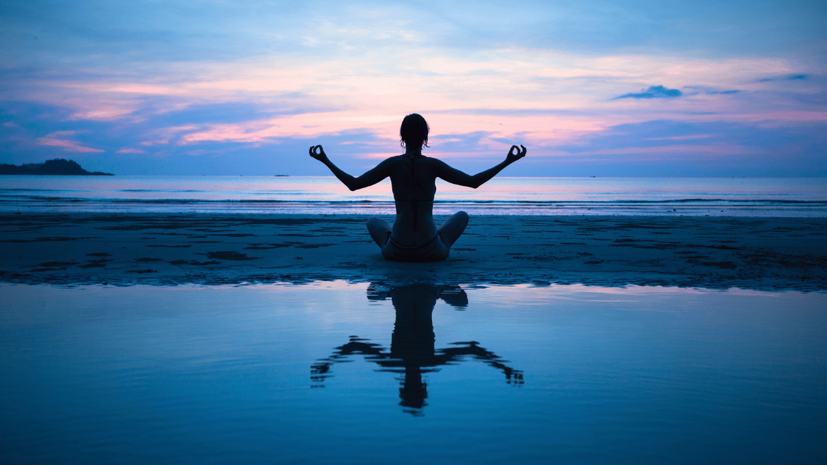 Woman meditating peacefully on the beach MSN