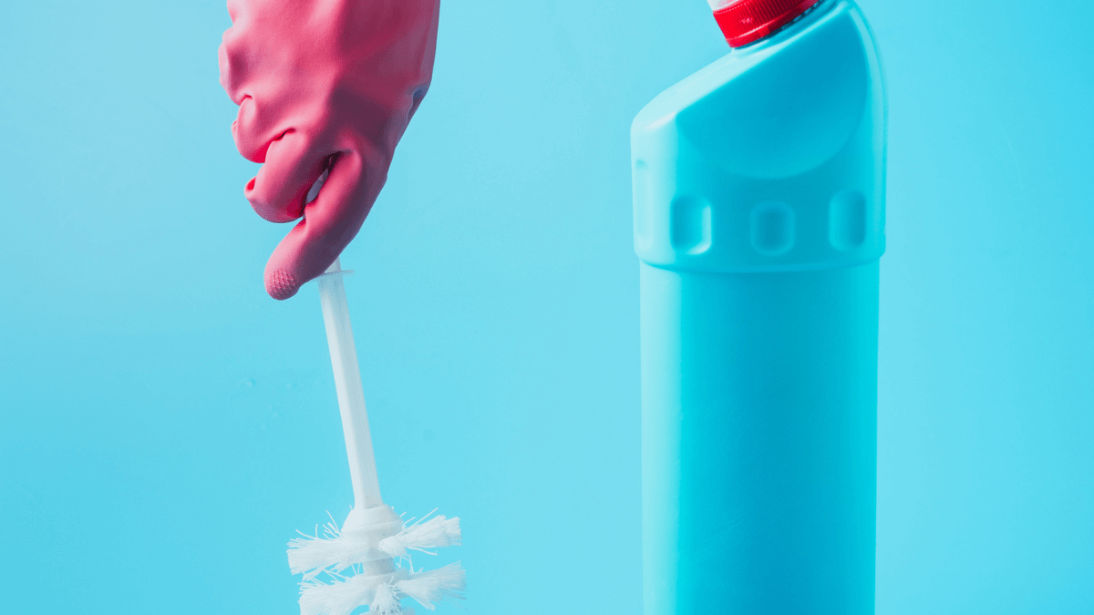 Cleaner holding toilet brush near cleaning fluid