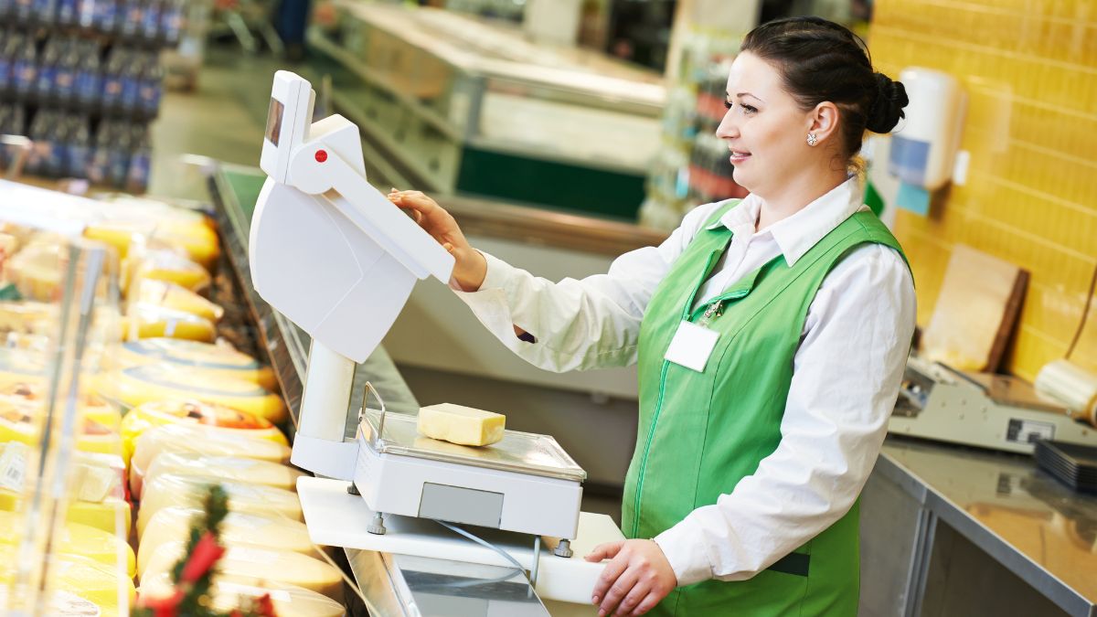 Beautiful retail worker weighing cheese MSN