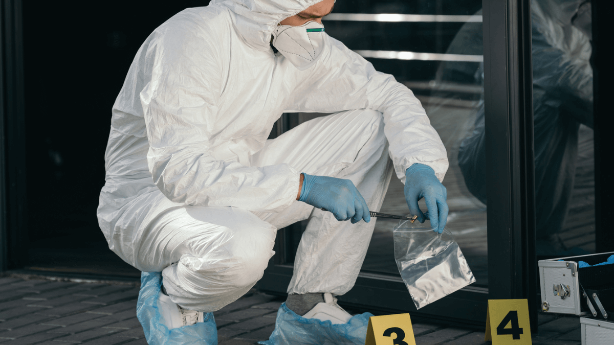 Male criminologist in protective suit at crime scene
