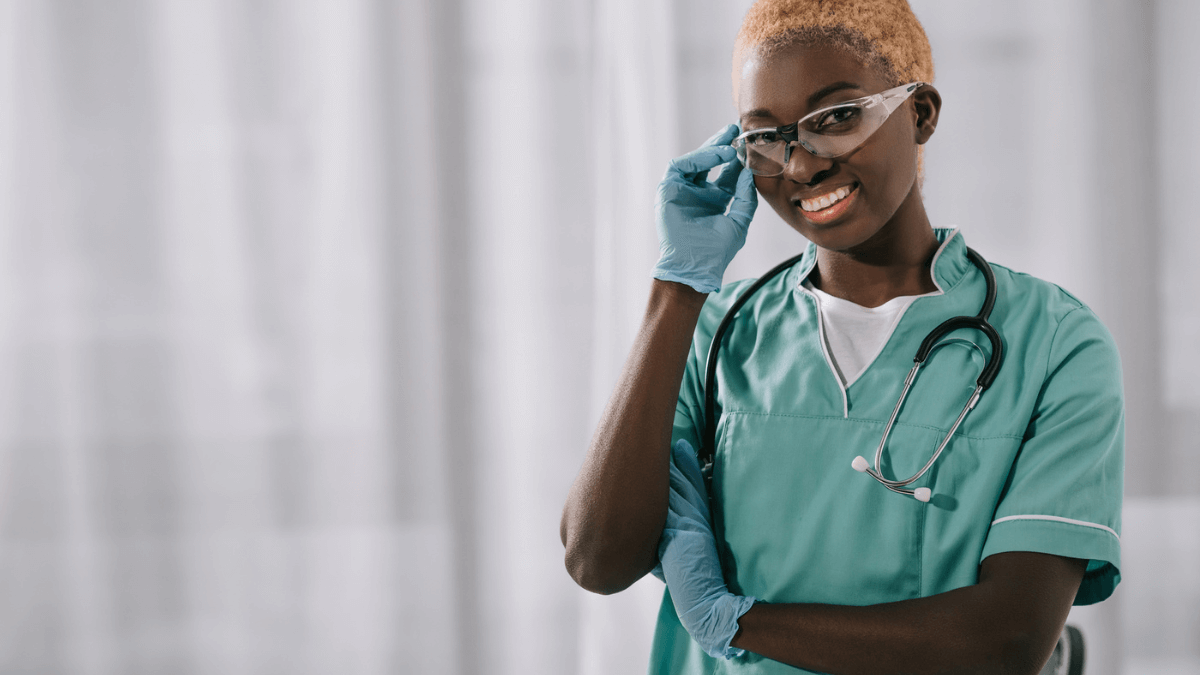 Smiling nurse in gloves holding goggles