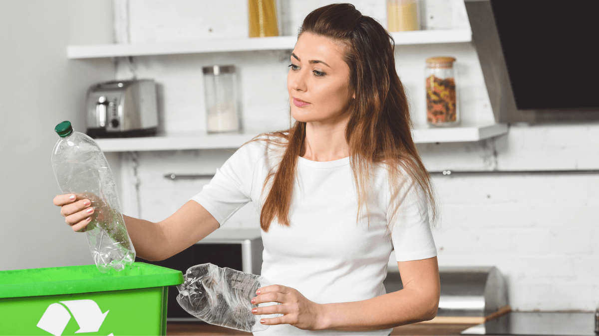 Woman putting plastic bottles in green recycle box
