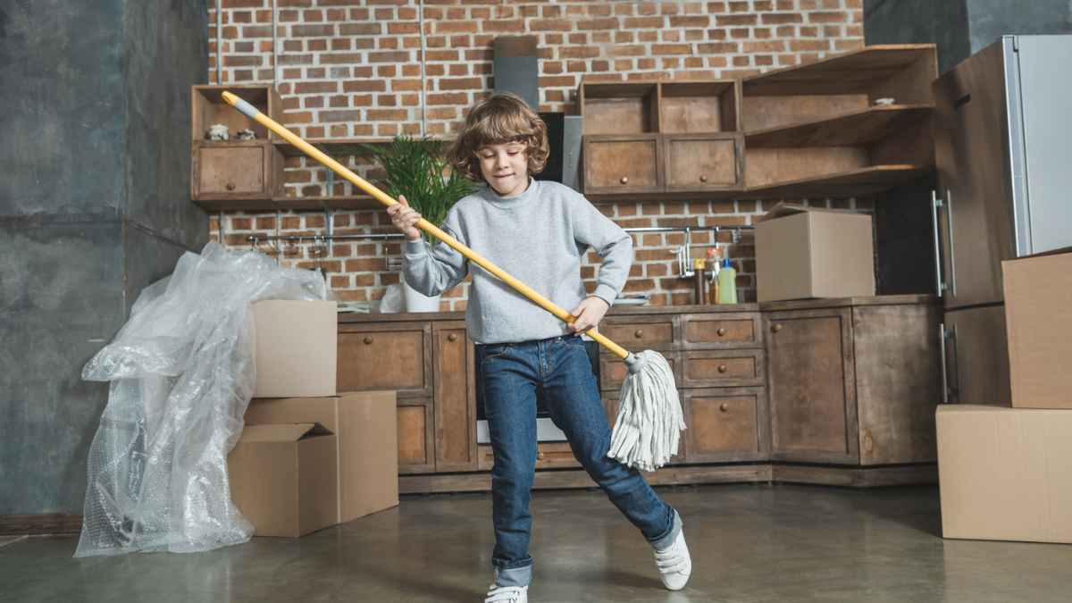 Cute happy little boy playing with mop in new apartment MSN.