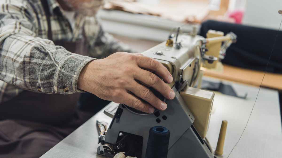 Male Tailor with Apron and Eyeglasses using the sewing machine MSN.