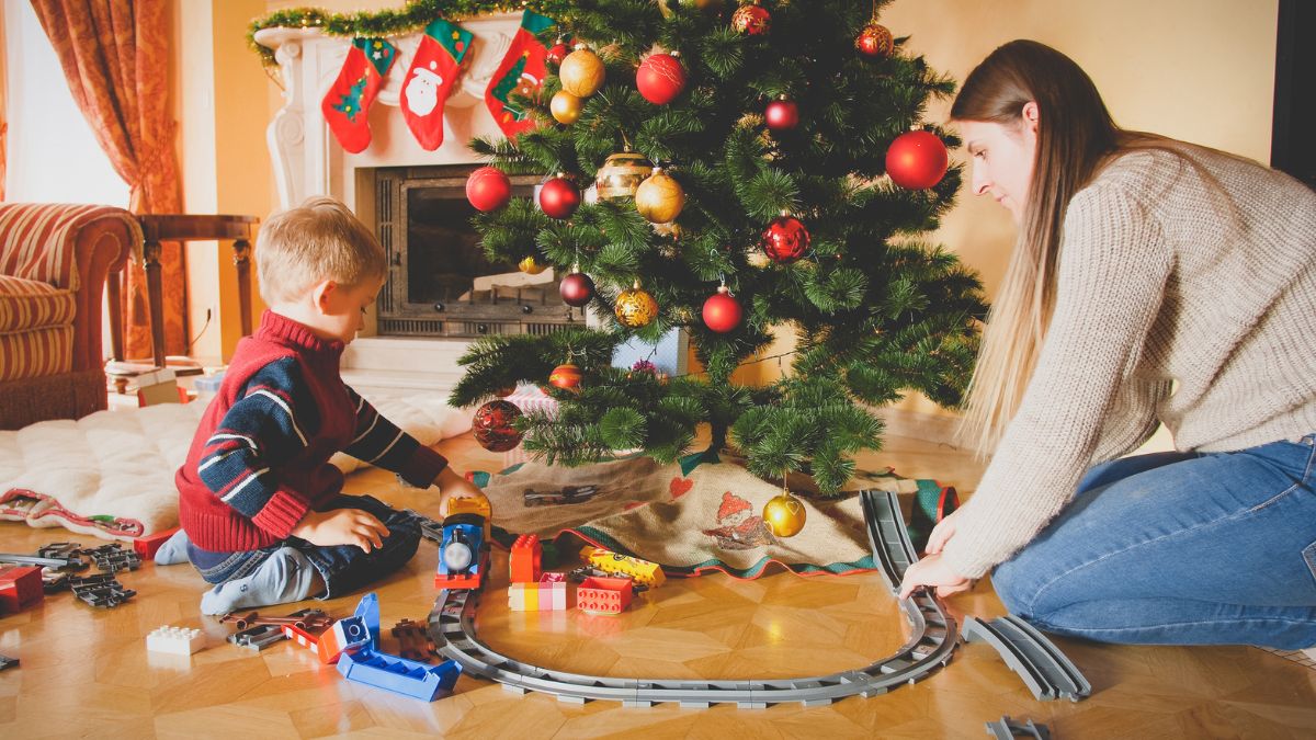 Mother and son play toy train around the Christmas tree MSN
