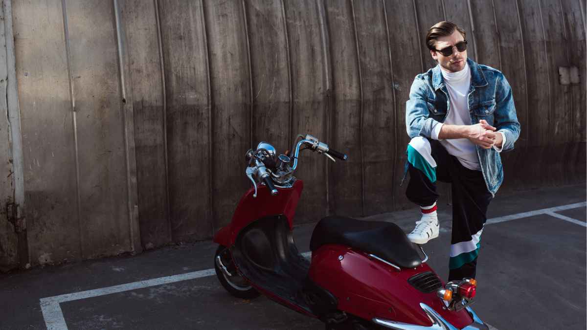 Serious man in stylish denim jacket with vintage scooter on parking MSN.