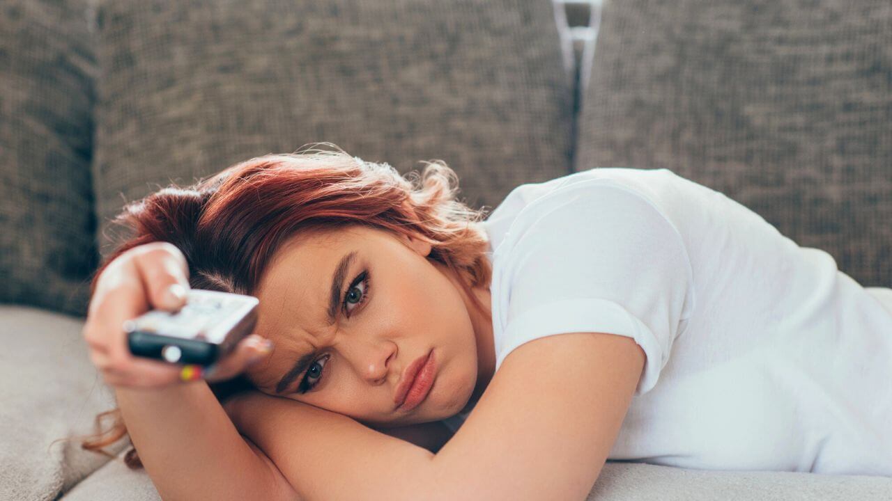 Angry Girl With Remote Controller Watching TV at Home