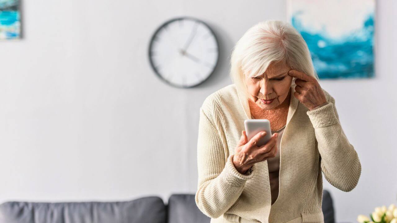 Senior Woman Touching Head While Using Smartphone