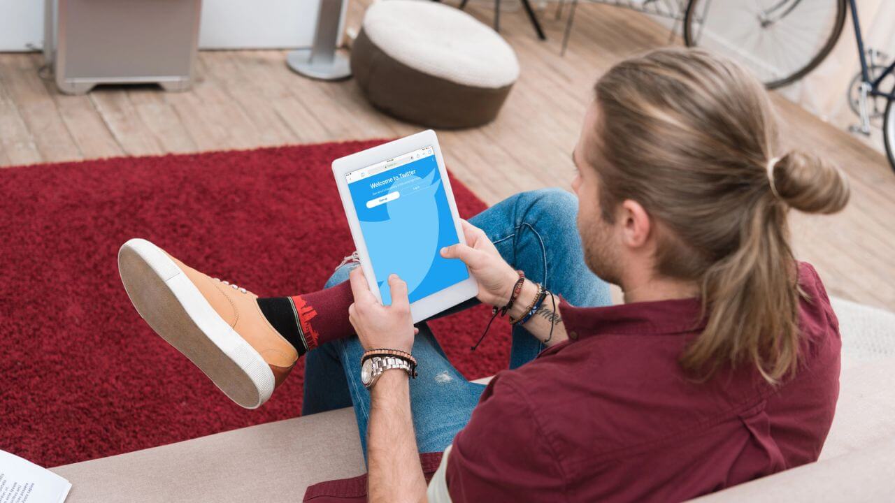 Man Sitting on Sofa While Using Digital Tablet with Twitter Application