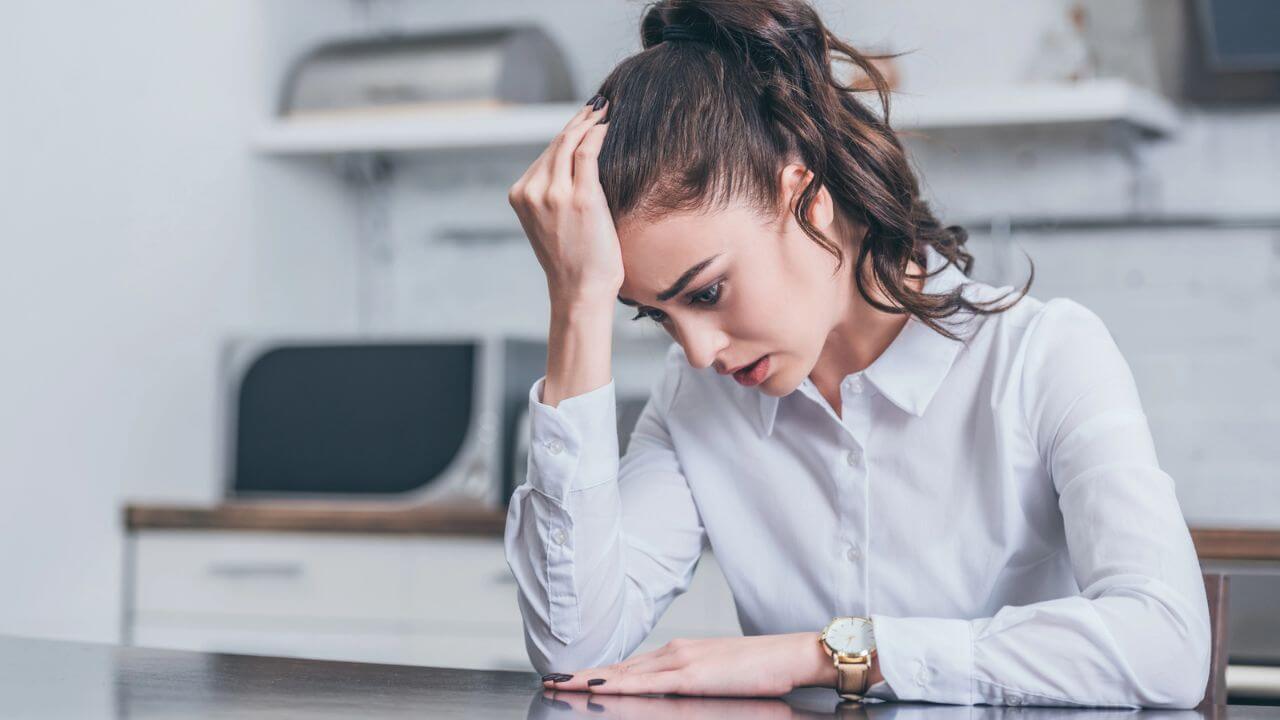 Upset Woman in White Blouse Sitting at Table